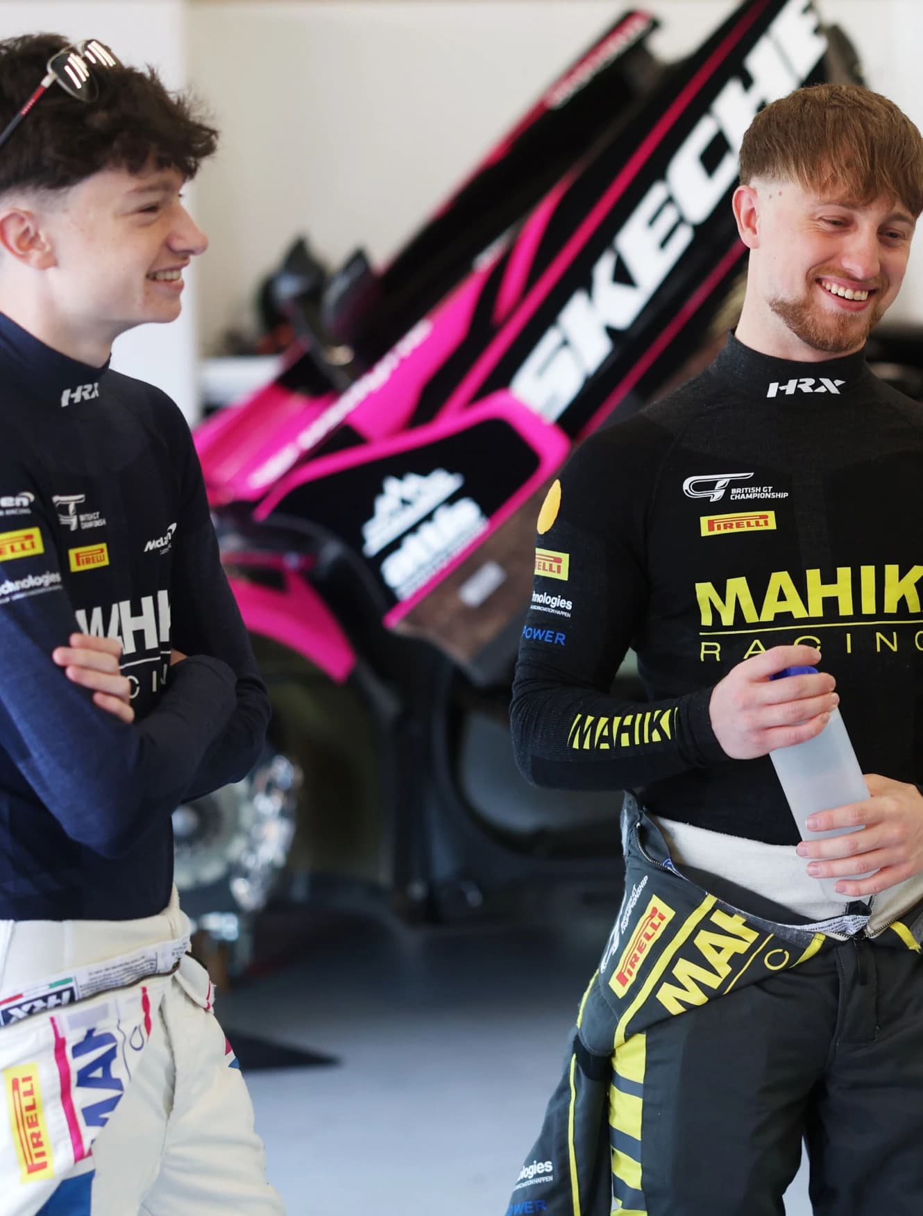 Revie Lake and his team mate in race suits talking in the garage beside the car