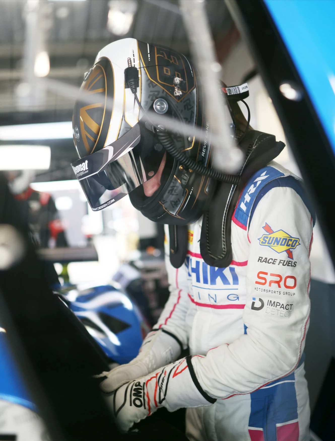 Revie Lake helmeted and on the radio, leaning into the car in the garage