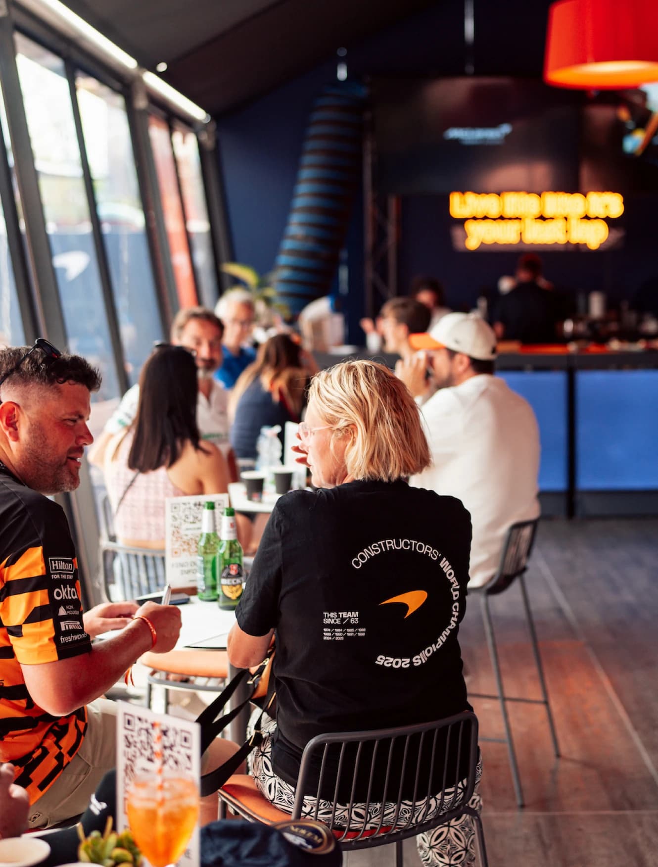 Guests sitting with drinks at tables in the McLaren hospitality suite
