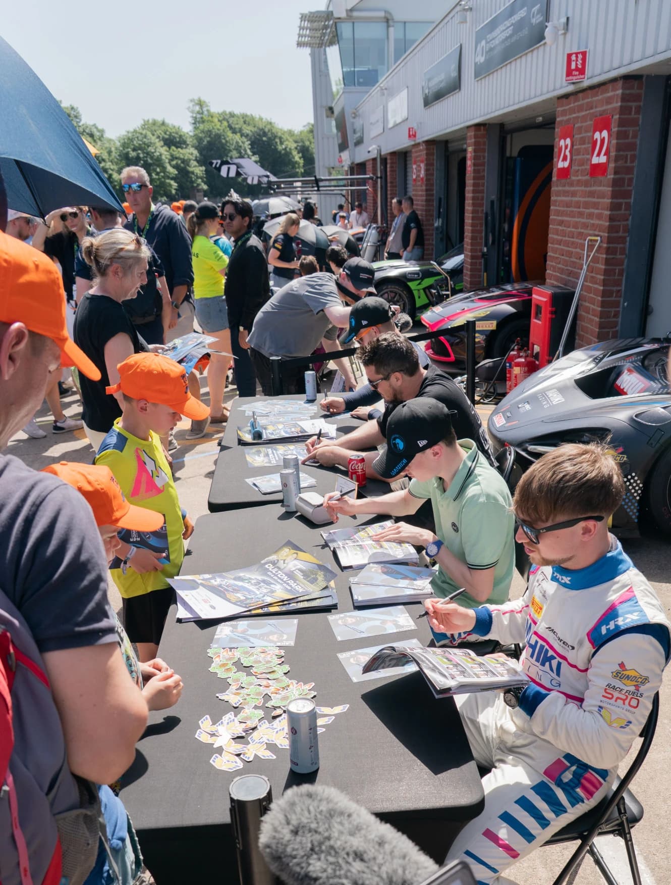Revie Lake and his team mate signing posters for fans at a trackside table