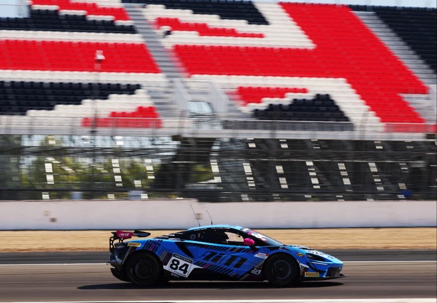 The number 84 Mahiki Racing McLaren Artura GT4 at speed past the grandstands at Silverstone