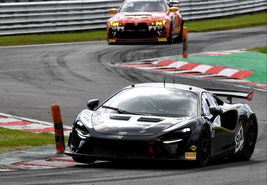 The black number 84 Mahiki Racing McLaren Artura GT4 through a corner at Oulton Park with another GT4 car behind