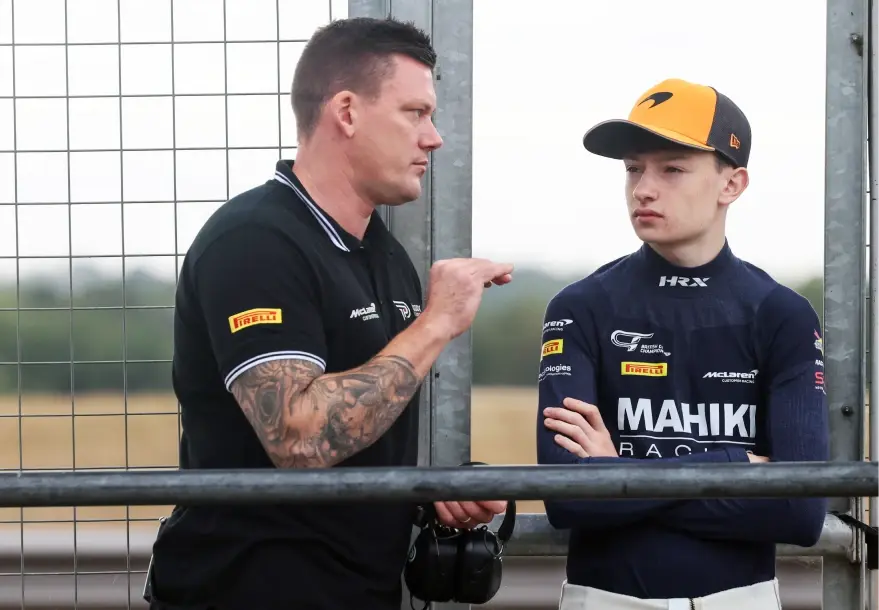 Revie Lake talking with a Mahiki Racing team member at the trackside fence at Snetterton