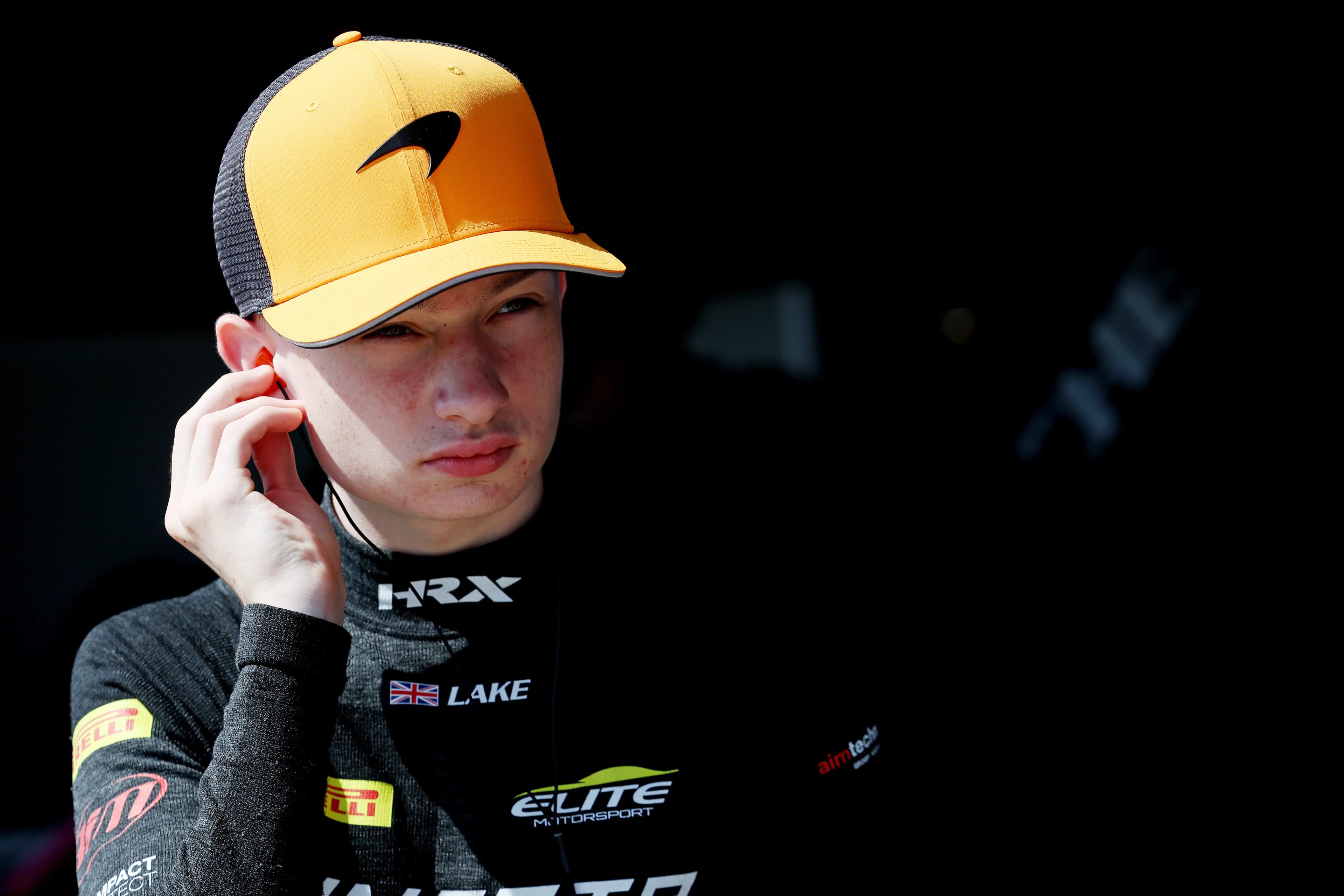 Revie Lake in Elite Motorsport race kit and a McLaren cap, fitting his earpiece before a session