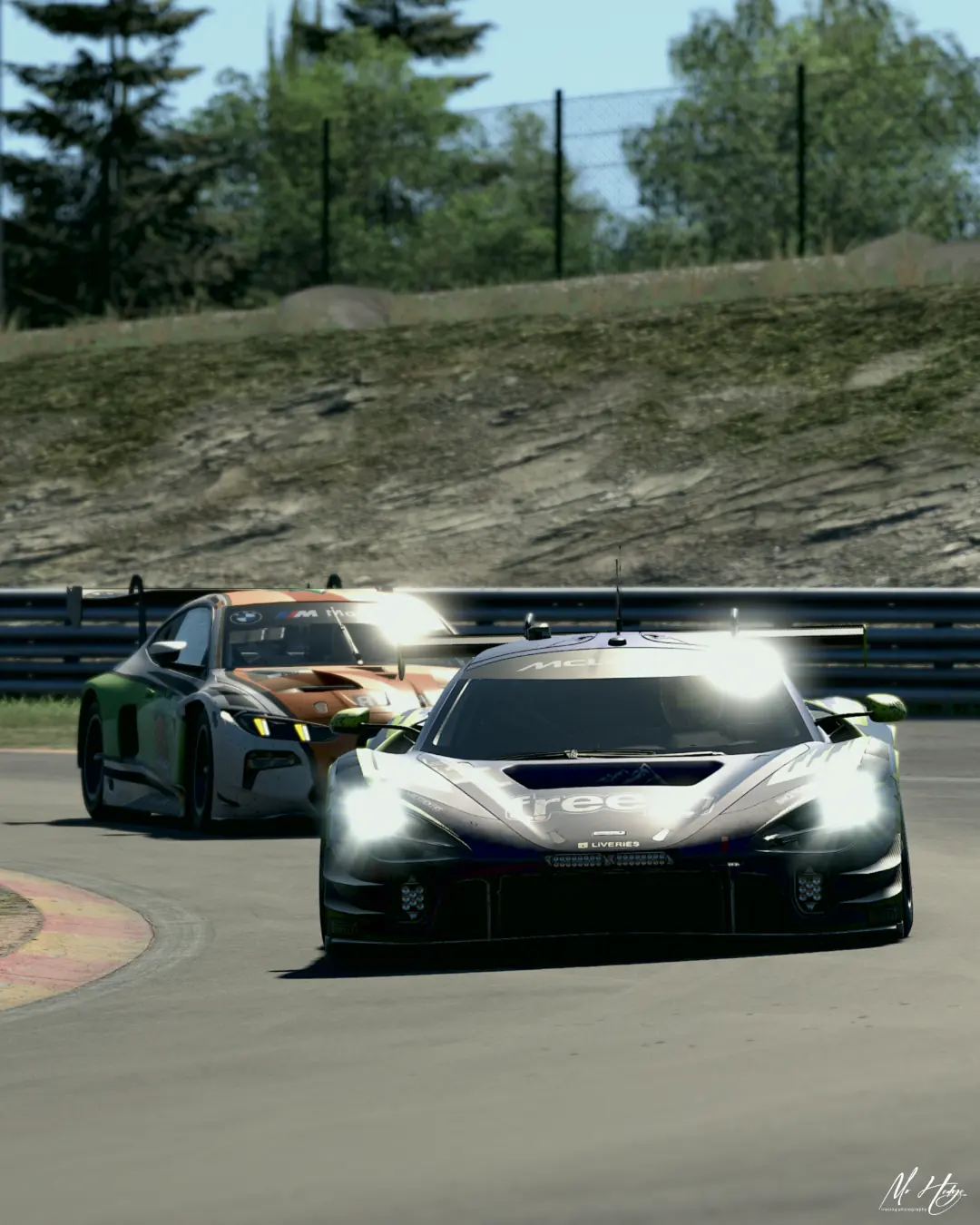 The number 114 Altitude Esports McLaren 720S GT3 ahead of a BMW M4 GT3 through a Spa-Francorchamps corner